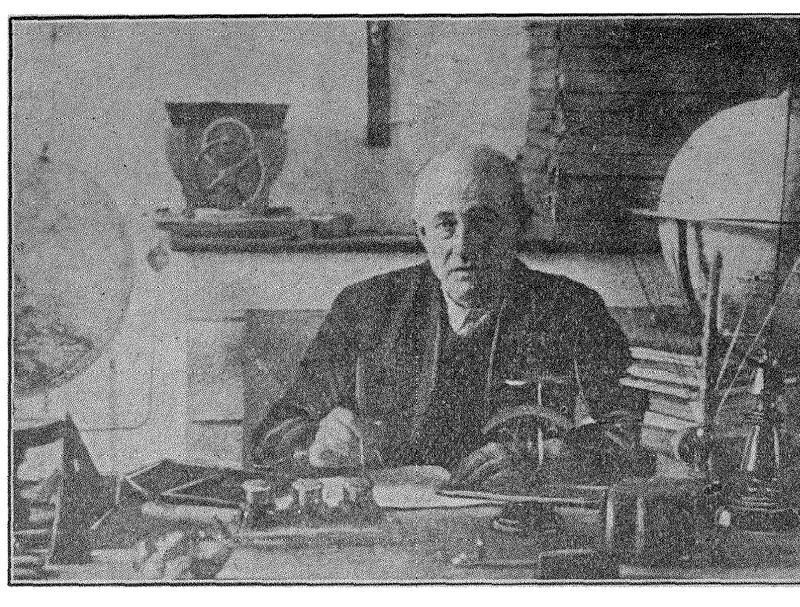 Justin Christofleau, an older man in a dark jacket, seated at a cluttered desk between two large globes, from his electroculture booklet
